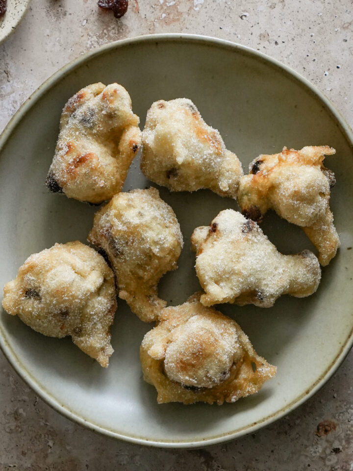 Zeppole covered in sugar in a shallow bowl