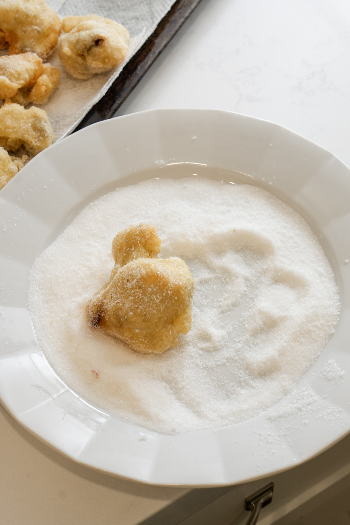 One zeppola in a dish with granulated sugar